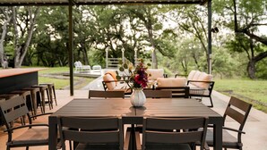 An outdoor patio with a table, chairs, a sofa, and a bar area.