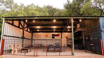 A covered outdoor area with a metal roof, a fenced enclosure, and a flag.