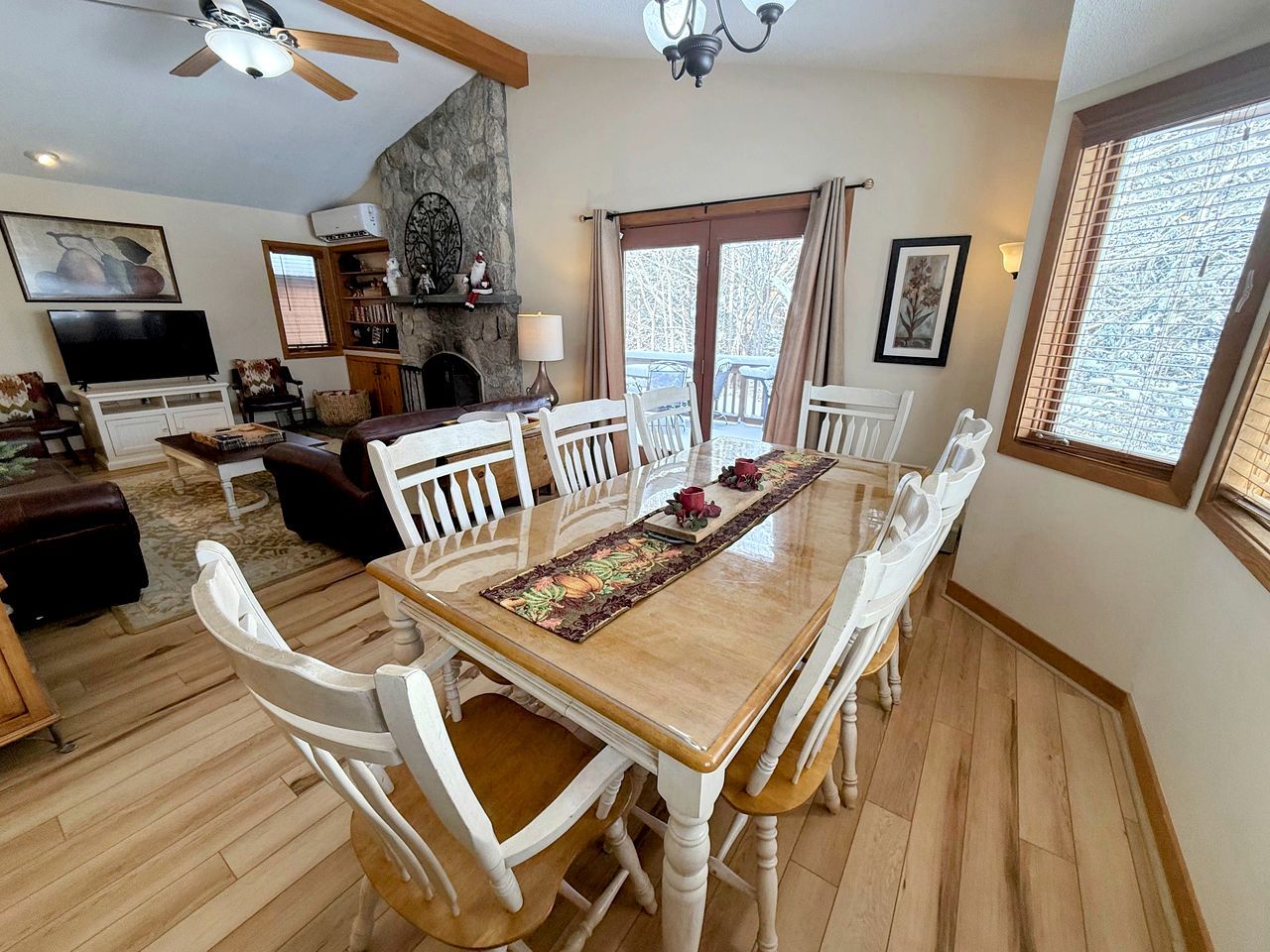 A dining area with a wooden table, white chairs, and a decorative runner.