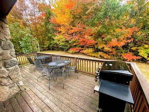 A wooden deck with a barbecue grill and outdoor furniture.
