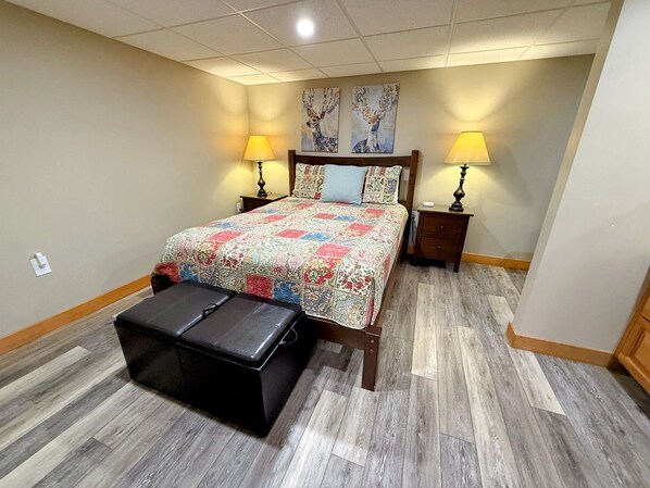 A bedroom with a bed, two bedside tables, a nightstand, a bench, and two wall-mounted lamps.