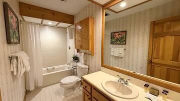 A bathroom with a bathtub, toilet, sink, and mirror.