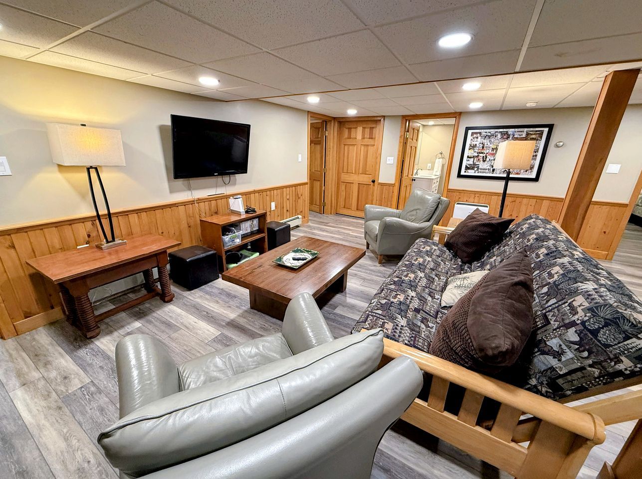 A modern living room with a wooden coffee table, leather sofa, and a flat-screen TV mounted on the wall.