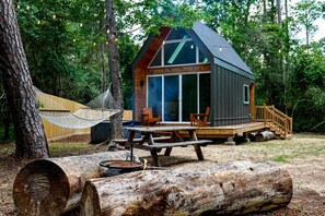 A cabin with a deck, a hammock, a picnic table, and a fire pit. - Luxury Cabin with Private Hot Tub - Cueta, Montgomery, TX (Montgomery)