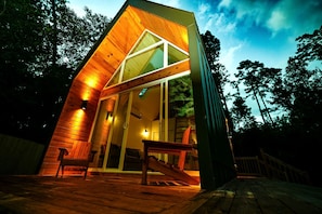 A modern wooden cabin with a sloped roof, large glass windows, and a wooden deck. - Luxury Cabin with Private Hot Tub - Cueta, Montgomery, TX (Montgomery)