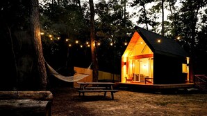 A cabin with a porch, a hammock, and string lights. - Luxury Cabin with Private Hot Tub - Cueta, Montgomery, TX (Montgomery)