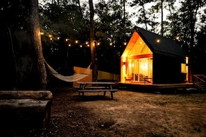 A cabin with a porch, a hammock, and string lights. - Luxury Cabin with Private Hot Tub - Cueta, Montgomery, TX (Montgomery)
