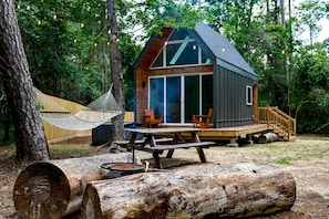 A cabin with a deck, a hammock, a picnic table, and a fire pit. - Luxury Cabin with Private Hot Tub - Cueta, Montgomery, TX (Montgomery)