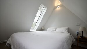 A bedroom with a skylight, a bed, two bedside tables with lamps, and a power outlet. - Luxury Cabin with Private Hot Tub - Cueta, Montgomery, TX (Montgomery)