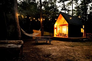 A cabin with a porch, a hammock, and string lights. - Luxury Cabin with Private Hot Tub - Cueta, Montgomery, TX (Montgomery)