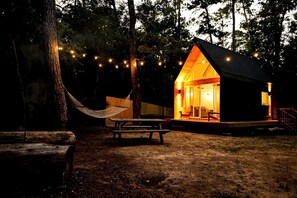 A cabin with a porch, a hammock, and string lights. - Luxury Cabin with Private Hot Tub - Cueta, Montgomery, TX (Montgomery)