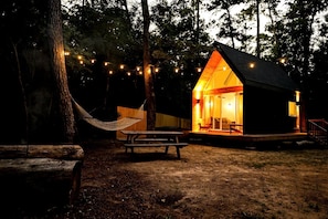 A cabin with a porch, a hammock, and string lights. - Luxury Cabin with Private Hot Tub - Cueta, Montgomery, TX (Montgomery)