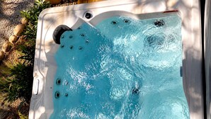 A hot tub with multiple jets, surrounded by a garden with plants and pebbles. - Fantastic Secluded Cabin in Monteagle, Tennessee (Monteagle)