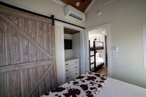 Une chambre avec un lit superposé, une armoire et un appareil de climatisation.
