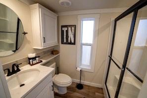 A bathroom with a toilet, sink, mirror, and a window. - Fantastic Secluded Cabin in Monteagle, Tennessee (Monteagle)