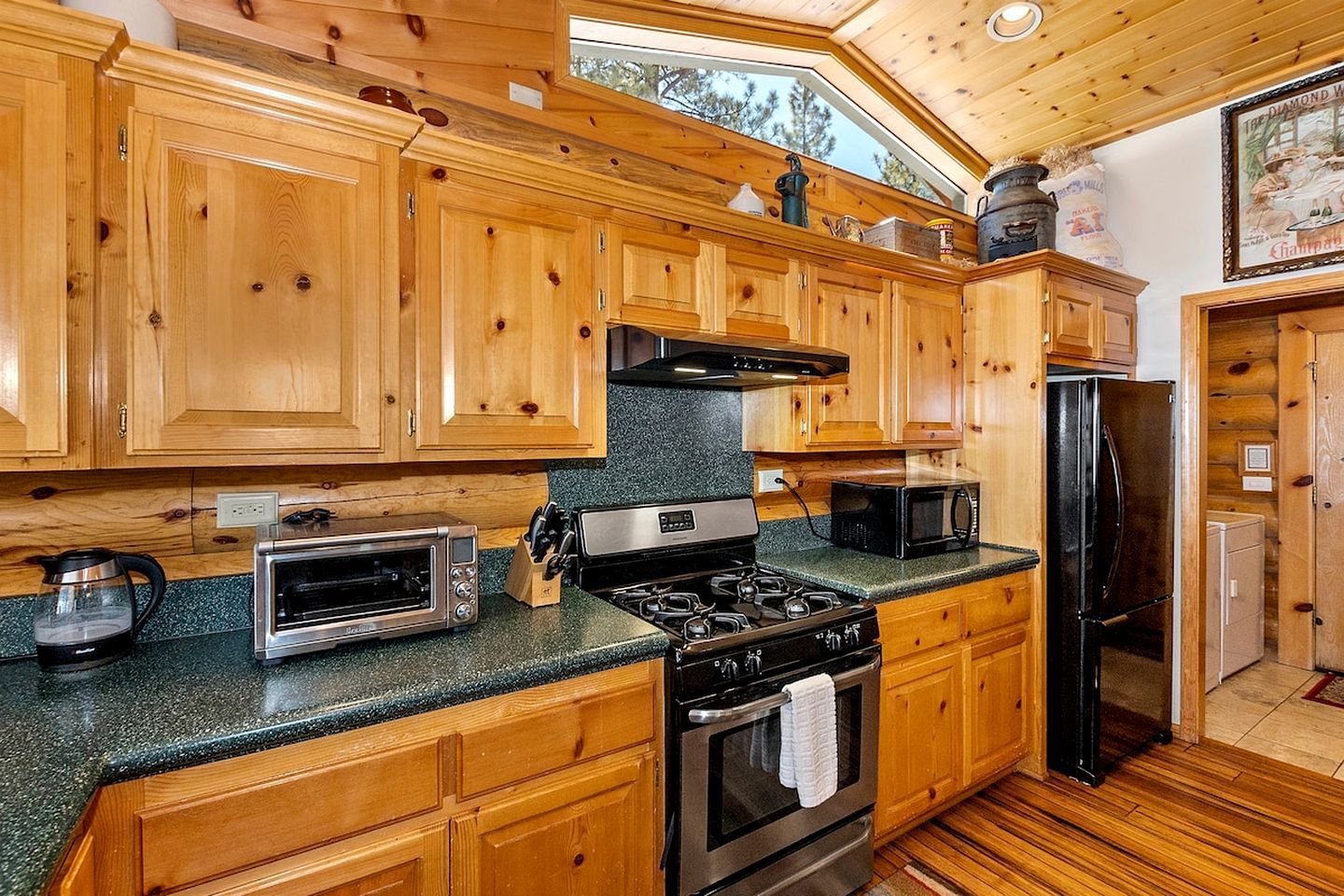 A wooden cabin kitchen with a stove, oven, microwave, and a refrigerator.