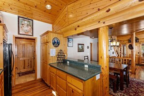 A wooden interior with a kitchen area featuring a granite countertop, wooden cabinets, and a refrigerator. - Escape to Adventure: Mountain Cabin Holidays in Big Bear Lake (Big Bear Lake)