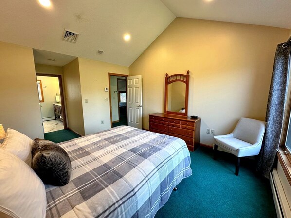 A bedroom with a bed, dresser, chair, and a mirror.