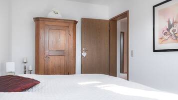 Ein Schlafzimmer mit einem Bett, einem Holzschrank, einer Tür, einem Wandbild und Nachttischlampen.