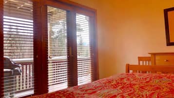 Un dormitorio con una cama, un aparador de madera y una puerta corrediza de vidrio que da a un balcón.
