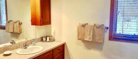 A bathroom with a sink, mirror, wooden cabinets, and towels on a rack.