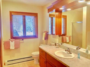 Ein Badezimmer mit Fenster, zwei Waschbecken, einem Spiegel und einer Toilette.