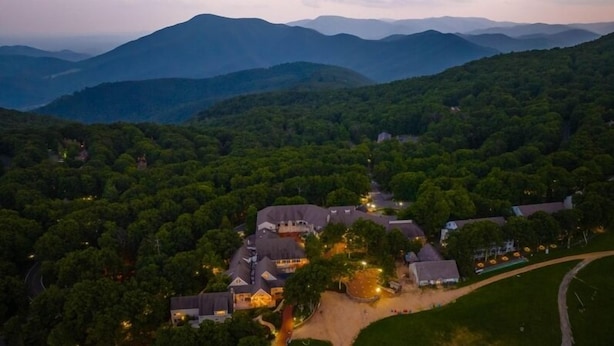 An aerial view of a large estate with multiple buildings surrounded by dense forest and mountains in the background. - Dobie 21 With Wintergreen Advantage (Wintergreen)
