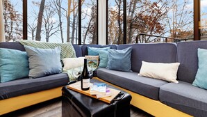 A modern living room with a sectional sofa, a wooden coffee table, and a large window offering a view of trees and sky. - Dobie 21 With Wintergreen Advantage (Wintergreen)