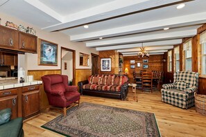 A spacious living room with a red armchair, a patterned sofa, and a dining area with wooden furniture. - Cozy Cabin with Sauna, Barbecue and Fireplace in Big Bear Lake, California (Big Bear Lake)