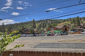 A parking lot with multiple cars, a building with a green sign, and a forested hillside in the background. - Cozy Cabin with Sauna, Barbecue and Fireplace in Big Bear Lake, California (Big Bear Lake)