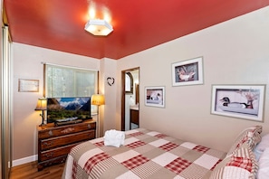 A bedroom with a bed, dresser, television, lamp, and framed pictures on the wall. - Cozy Cabin with Sauna, Barbecue and Fireplace in Big Bear Lake, California (Big Bear Lake)