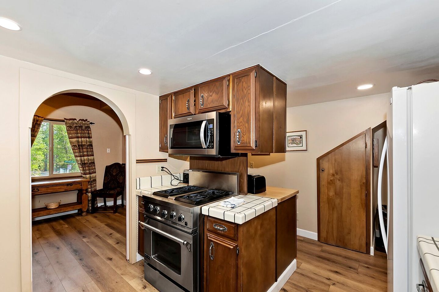 A compact kitchen with a microwave, stove, and wooden cabinets.