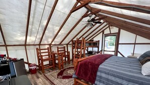 A tented room with a bed, a desk, and a chair.
