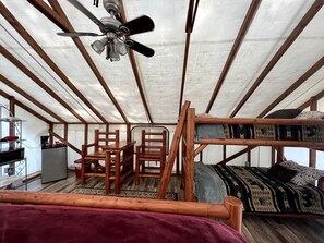 A tent-style room with a bunk bed, a desk, chairs, a refrigerator, and a ceiling fan. - Safari Tent Rental for a Glamping Getaway near Olympic National Park in Washington (Belfair)