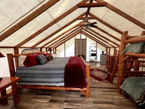 Ein Zimmer mit hohen Decken, einem Bett, Holzmöbeln und Blick durch ein Fenster.