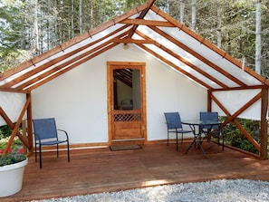 A wooden structure with a pitched roof, a door, and two tables with chairs. - Charming Camping Getaway near Olympic National Park in Washington (Belfair)