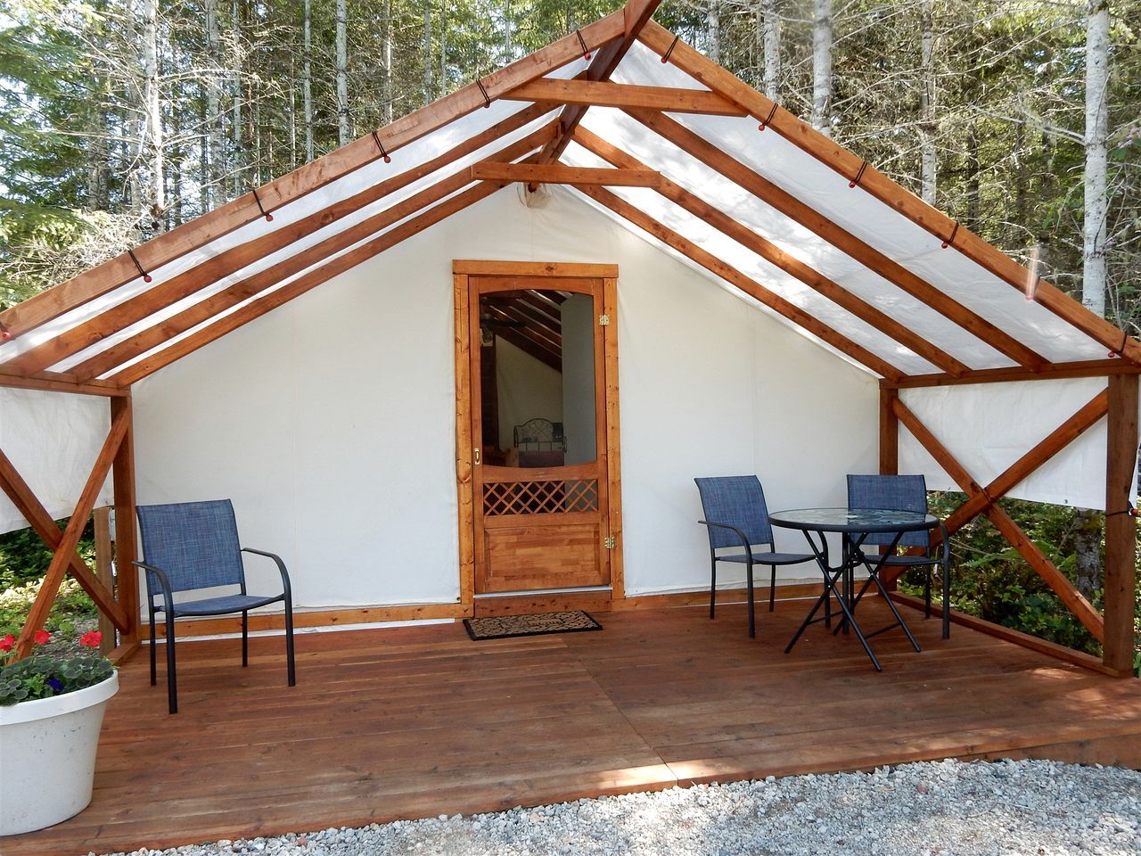 Eine Holzhütte mit Satteldach, einer Tür und zwei Tischen mit Stühlen.