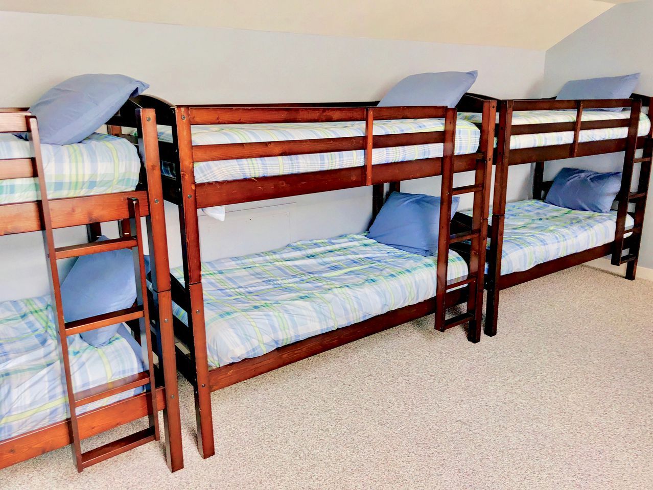 Une chambre avec un lit superposé, dont la structure est en bois et le linge de lit est à carreaux.