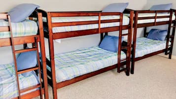 Une chambre avec un lit superposé, dont la structure est en bois et le linge de lit est à carreaux.