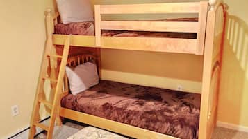 A bunk bed with a ladder, a pillow, and a patterned rug.