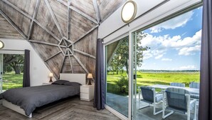 Un dormitorio con una cama grande, mesitas de noche, vistas al exterior y un tragaluz.