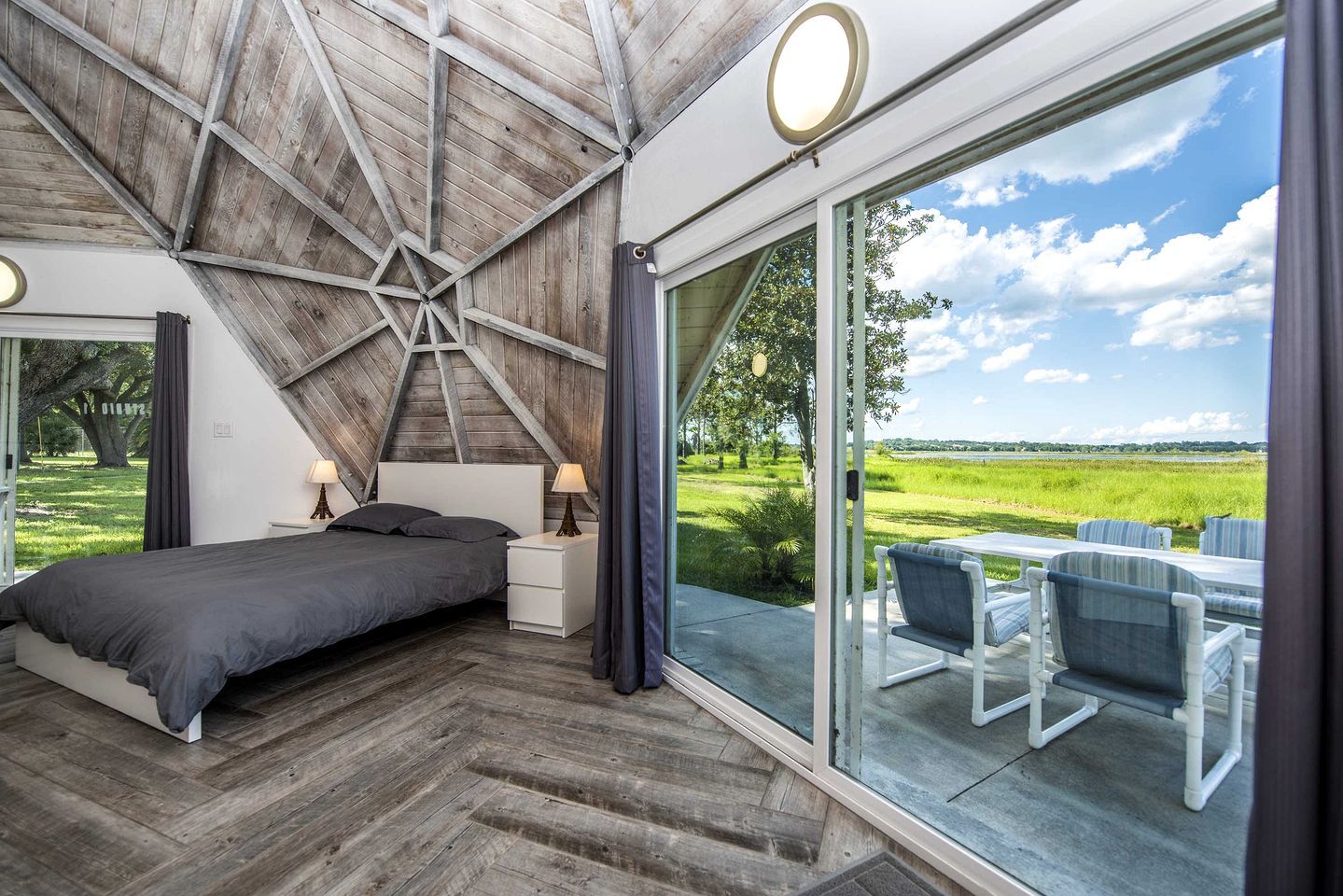 A bedroom with a large bed, bedside tables, a view of the outdoors, and a skylight.