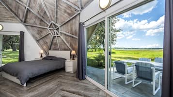 A bedroom with a large bed, bedside tables, a view of the outdoors, and a skylight.