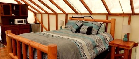 Una cama de madera con ropa de cama estampada en una habitación con techo inclinado y vigas de madera.