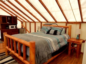 A wooden bed with patterned bedding in a room with a sloped ceiling and wooden beams.