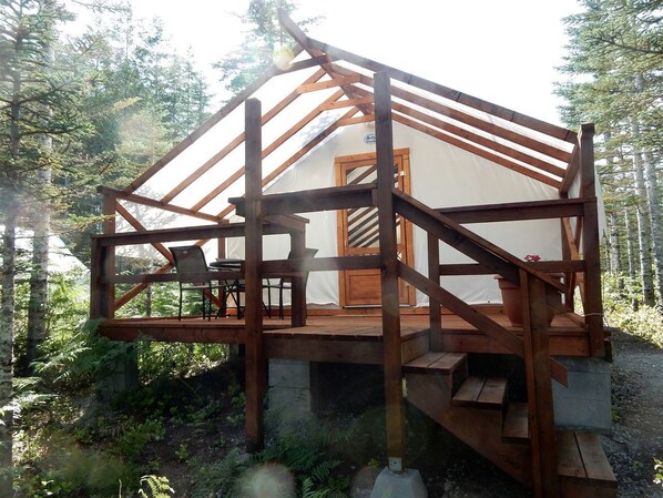 Eine Holzterrasse mit einer Treppe, die zu einem weißen Gebäude mit einer Tür führt.