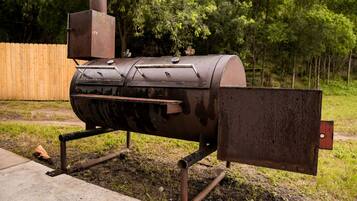 En grill med grillspyd, hylde og metaldæksel.