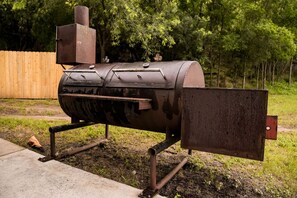 A barbecue grill with a chimney, a side shelf, and a metal cover. - Gorgeous Tiny House with Fire Pit, Games and Barbecue in San Saba, Texas (San Saba)