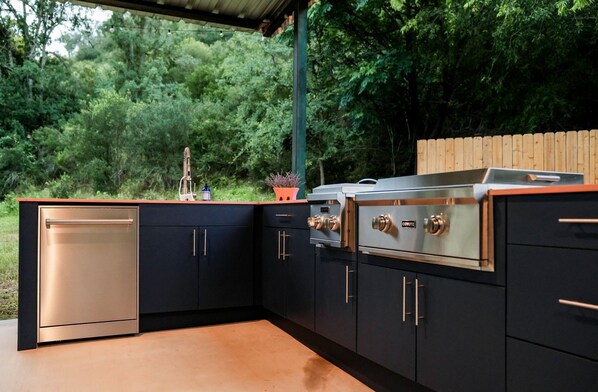 A modern outdoor kitchen with a built-in oven, a sink, and a countertop. - Gorgeous Tiny House with Fire Pit, Games and Barbecue in San Saba, Texas (San Saba)