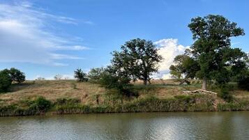 A calm river with boats, trees, and a clear sky.
